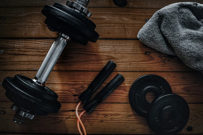 Dumbbells and a jump rope on a wooden training surface.